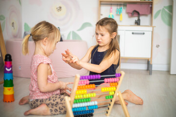 Naklejka premium Little children in kindergarten learn to count on abacus, bright wooden toys in the nursery