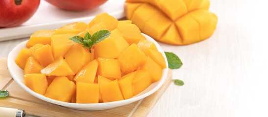 Diced fresh mango fruit on a white plate with leaves.