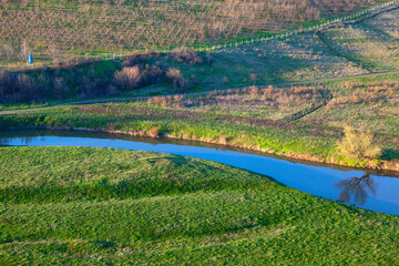 Gardens meadows and riverside valley . peaceful scenery with flowing river . Rustic fields in the springtime