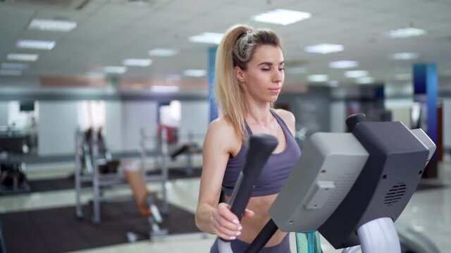 Young woman working out on orbi track at gym exercising