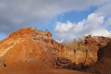 Red hills with birches against a blue sky.