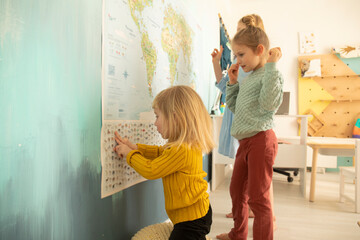 Caucasian children study geography, sisters look at the world map, home education, classroom interior, home education for children