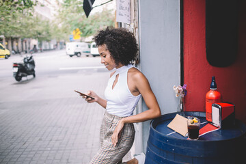 Young black woman messaging in outdoor cafe