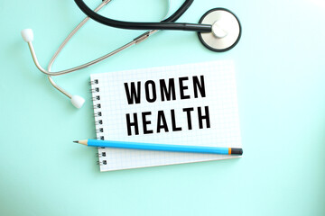 White notepad with the words WOMEN HEALTH and a stethoscope on a blue background.