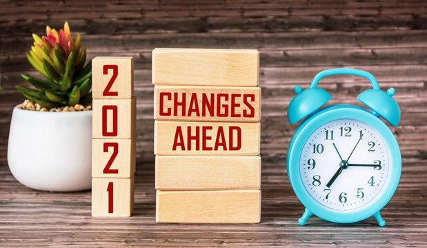 CHANGES AHEAD 2021 Concept written on wooden blocks and cubes Alarm clock and cactus stands on wooden table with change in 2021 concept.