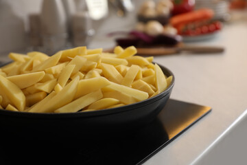 Frying pan with cut raw potatoes on cooktop, closeup. Space for text