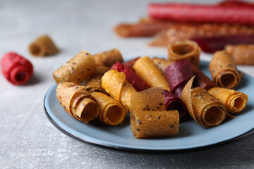 Delicious fruit leather rolls on grey table, closeup