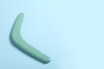 Wooden boomerang on light blue background. Space for text