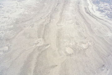 A winding trail in the sand, formed by sea waves on the beach. View from above.