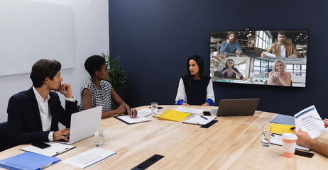 Diverse group of business colleagues having video call on screen in meeting room