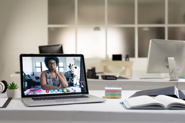 Laptop computer with a video call from businesswoman lying on desk