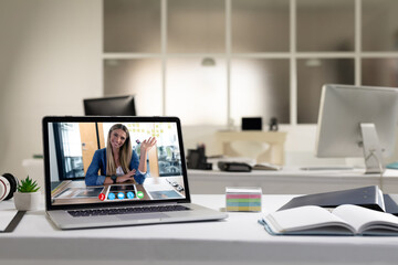 Laptop computer with a video call from businesswoman lying on desk