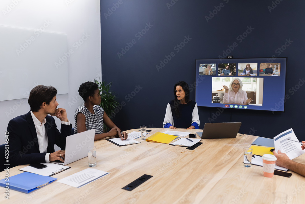 Wall mural Diverse group of business colleagues having video call on screen in meeting room