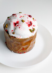 Easter muffin cake with pistachios and cranberry and easter decorations on a white plate. White background. Copy space. 