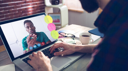 Caucasian businessman sitting at desk using laptop having video call with male colleague