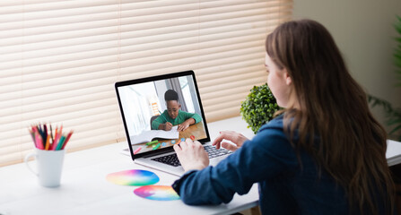 Fototapeta na wymiar Caucasian girl sitting at desk using laptop to talk to friend