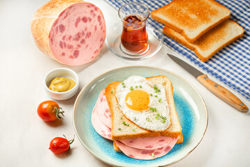 Easy breakfast - fried egg on sandwich with sausage on plate with tomatoes, mustard, ham, toast.