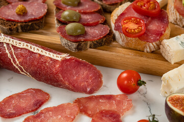 Assortment of sausages and cheese, salami camembert brie slices, olives, on white background. Close up