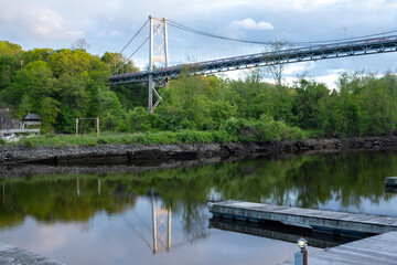 Kingston, NY - USA- May 12, 2021: a landscape view of the Wurts Street Bridge or the The Kingston–Port Ewen Suspension Bridge, is a steel suspension bridge spanning Rondout Creek.