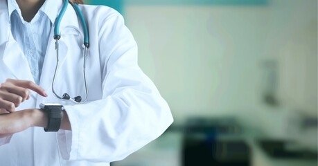 Composition of midsection of female doctor in lab coat using smartwatch over out of focus hospital