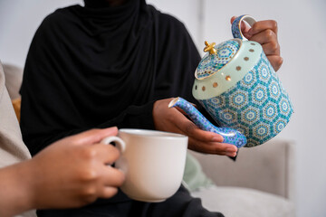 Two Black Muslim women having cake and dessert at home