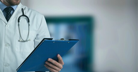 Composition of midsection of male doctor in lab coat holding clipboard over out of focus hospital