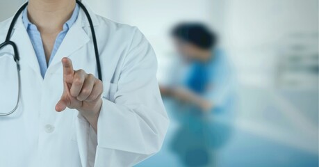 Composition of midsection of male doctor in lab coat pointing over out of focus hospital