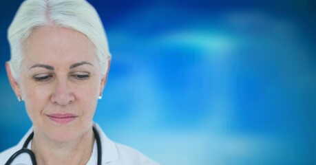 Caucasian senior female doctor wearing stethoscope against blue gradient background