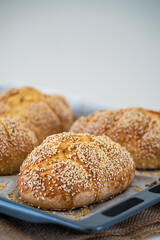 Fresh challah bread rolls hot from the oven on baking tray. Gluten free bread buns or mini loaves with sesame seeds and golden color ready to eat. Fluffy shaped bread for sandwiches, lunch and dinner.