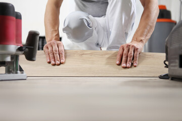 Worker hands installing timber laminate vinyl floor. Wooden floors house renovation.