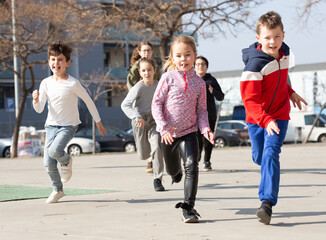 Large group of playful children running together at urban landscape