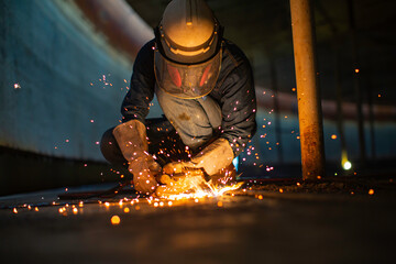 Male worker metal cutting spark on tank bottom steel plate with flash of cutting light close up wear protective gloves and mask - Powered by Adobe