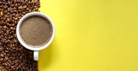Horizontal banner with a cup of coffee and coffee beans on a yellow background. Top view. Copy space. Espresso or Americano in a cup.