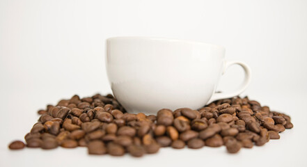 White mug rests on top of a lot of coffee beans.