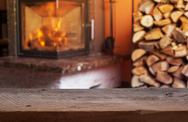 Old wooden table and fireplace with warm fire on the background.