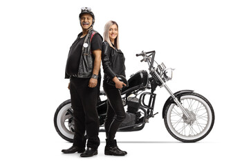 Obraz premium Mature biker and a young woman in leather clothes posing in front of a chopper