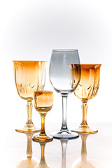 four goblet glasses orange and gray on a light background with reflection