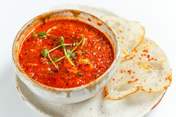 bright orange tomato cream soup with sprouts of young peas and croutons, on a light background, close-up, restaurant serving