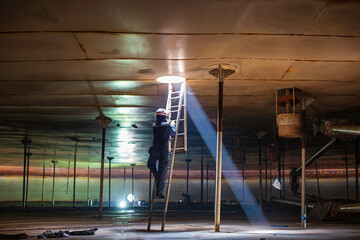 Male worker climb inside the stairway storage visual inspection tank into the confined space