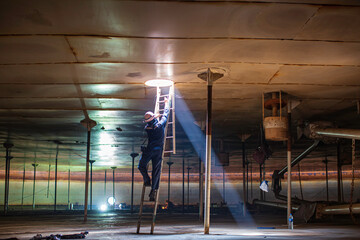 Male worker climb inside the stairway storage visual inspection tank into the confined space
