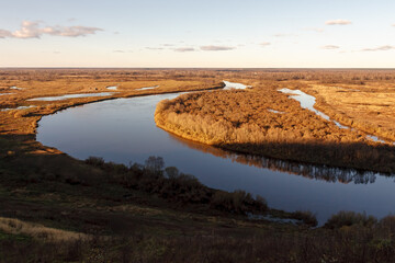 beautiful bend of the river at sunset, big shadow, floodplain, autumn, orange forest, blue transparent sky with clouds