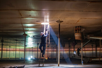 Male worker climb inside the stairway storage visual inspection tank into the confined space