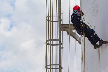 Male worker rope access height safety inspection of thickness storage oil and gas tank