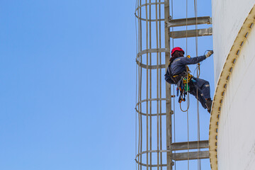 Fototapeta premium Male worker rope access height safety inspection of thickness storage oil and gas tank