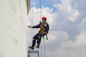 Male worker rope access height safety inspection of thickness storage oil and gas tank