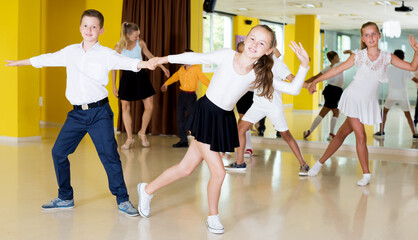 Fototapeta na wymiar Glad boys and girls enjoying active dance in studio