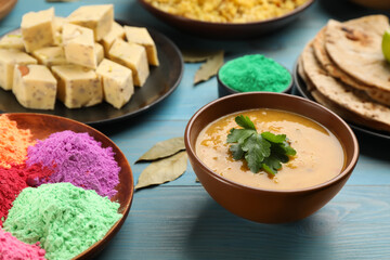 Traditional Indian food and color powders on light blue wooden table. Holi festival celebration