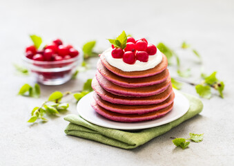Berry pancakes with cream on a plate on a linen napkin on a light background