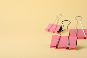 Binder clips on beige background, closeup. Space for text