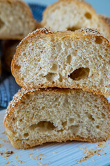 Fresh challah bread rolls hot from the oven cut into half. Crumb shot of gluten free bread buns or mini loaves with sesame seeds and golden color. Fluffy homemade bread wrapped in a towel ready to eat